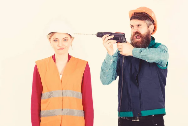 Annoying repair concept. Man with drill drills head of woman, white background. Husband annoyed wife. Woman with bored face in helmet, hard hat. Builder, repairman makes hole in female head.