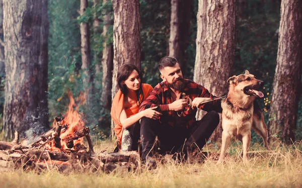 Paar mit Schäferhund am Lagerfeuer, — Stockfoto