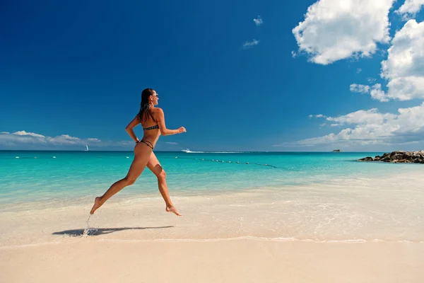 Woman with sexy body in swimsuit running on sea beach — Stock Photo, Image