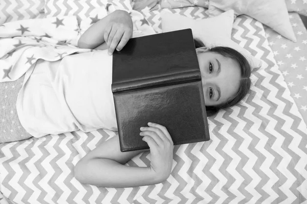 Fille enfant couché lit lire livre vue du dessus. Le gamin se prépare à aller se coucher. Agréable temps dans une chambre confortable. Fille enfant se détendre et lire le livre. Terminé la lecture et satisfait de la fin heureuse. Améliorer les compétences en lecture — Photo