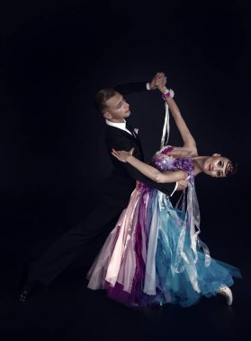 Dans eden balo çifti siyah arka planda yalnız poz verir.