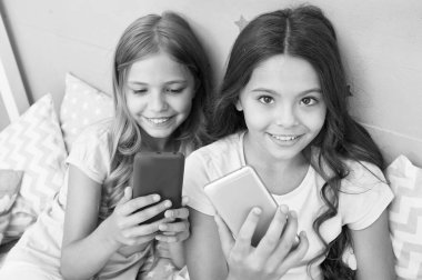 Pijama partisi konsepti. Kız kıza mutlu bir çocukluk. Akıllı telefonlu uzun saçlı kızlar modern teknoloji kullanır. Hadi selfie çekelim. Arkadaşlarının sosyal ağındaki fotoğrafını gönder. Çocuklar yatak odasında selfie çekiyor.