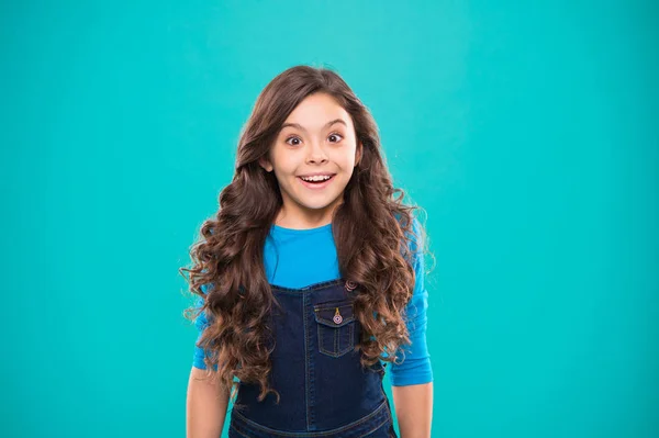 Kid girl long healthy shiny hair wear casual clothes. Little girl excited happy face. Kid happy cute face feels excited blue background. Sincere excitement. Exciting moments. Excitement emotion