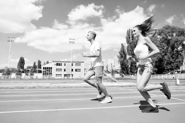 Familia joven que promueve un estilo de vida saludable. La mujer y el hombre dirigen el estadio. Entrenador y deportista de movimiento ejecutar el entrenamiento antes de la carrera. Un par de corredores entrenando al aire libre. Pareja o familia viven un estilo de vida saludable — Foto de Stock