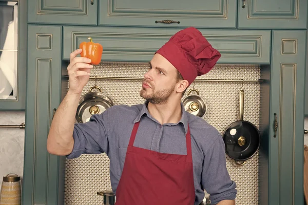 Chef look at sweet pepper in kitchen