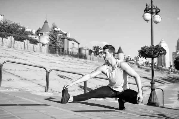Najdete rovnováhu. Muž cvičení venku městské pozadí. By se táhnou svaly po cvičení k dosažení nejlepšího výsledku. Sportovec, balancování na jedné noze při protahování. Příjemný roztáhnout po cvičení — Stock fotografie
