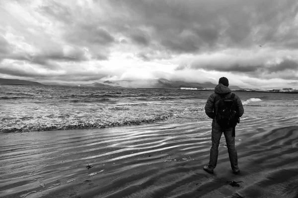 El hombre mira en el horizonte con el paisaje marino reykjavik en la tierra de hielo. concepto de metas futuras. amantes de la naturaleza. viajar y vagabundear. hombre en la orilla del mar mirar en el paisaje marino de pie cerca del agua. cielo dramático en iceland —  Fotos de Stock