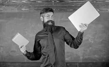 Öğretmen sakallı hippi kitap ve laptop tutar. Ne tercih ederim. Öğretmen modern öğretim yaklaşımı seçme. Kağıt kitap dizüstü karşı. Dijital kağıt karşı. Şu öğretim yöntemi seçin