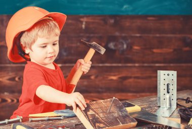 Yürümeye başlayan çocuk meşgul yüzündeki çekiç aracı evde atölye ile oynuyor. Kask Oluşturucu veya repairer, onarımı veya handcrafting olarak oynayan sevimli çocuk. Çocuk Çocuk tamirci oynamak. Handcrafting kavramı