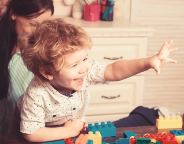 Yüzü gülen çocuk renkli plastik tuğlaların yanında..