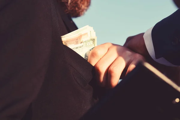 Man dressed in black suit holds folder takes bribe.