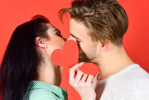 Couple amoureux embrasser et cacher les lèvres derrière la carte cardiaque. Baiser sensuel d'un couple charmant de près. Embrasse romantique homme et femme. Amour et préliminaires. Célébrez la Saint Valentin. Concept de baiser romantique — Photo