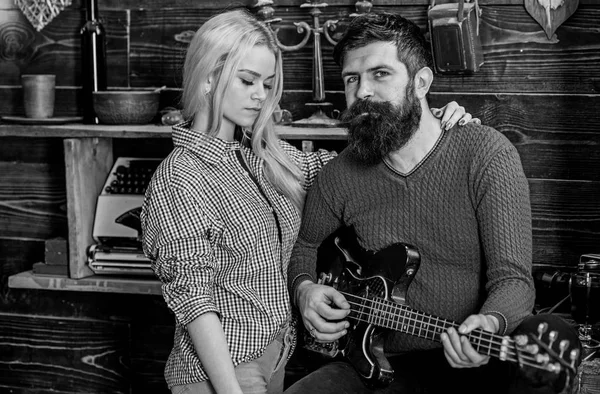 Concepto romántico de noche. Pareja enamorada pasar una velada romántica en un ambiente cálido. Señora y hombre con barba en caras de ensueño abrazos y toca la guitarra. Pareja en madera vintage interior disfrutar de la música de guitarra — Foto de Stock