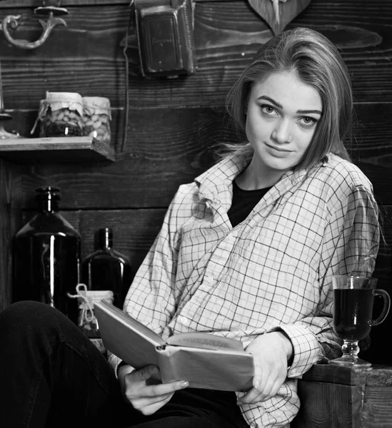 Μελέτη έννοιας. Κυρία στο ήρεμο πρόσωπο με τα καρό ρούχα φαίνεται χαριτωμένο και casual. Κορίτσι σε casual ντύσιμο κάθεται με το βιβλίο στο ξύλινο εκλεκτής ποιότητας εσωτερικό. Κορίτσι φοιτητής μελέτη με το βιβλίο στο σπίτι του εμπρηστή — Φωτογραφία Αρχείου