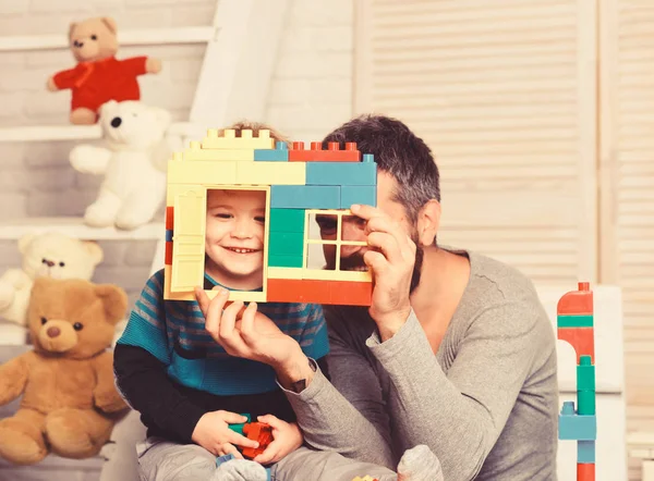 Dad and kid with toys on wooden background hold blocks — Stock Photo, Image