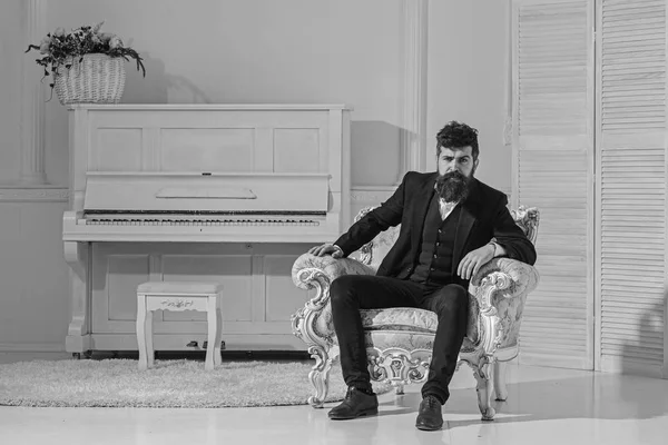 Maço çekici ve zarif eski moda koltukta oturan ciddi, düşünceli yüzünde. Servet ve zenginlik kavram. Sakal ve bıyık Klasik takım, şık şık kıyafet giyen adamla