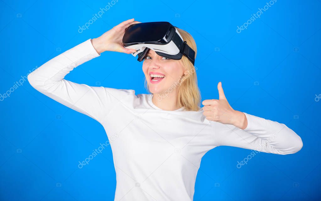 Amazed young woman touching the air during the VR experience. Woman watching virtual reality vision. Happy young woman wearing virtual reality goggles watching movies or playing video games.