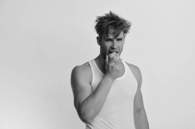 Atlet dağınık saçlı taze meyve yiyor. Meşgul yüz ışık gri arka plan üzerinde izole adamla. Diyet ve sağlıklı yaşam konsepti. Yeşil elma elinde olan adam