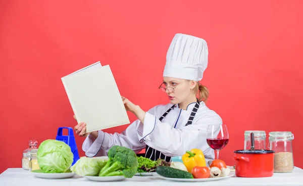 Γυναίκα σεφ μαγειρικής υγιεινά τρόφιμα. Κορίτσι διαβάσει βιβλίο επάνω καλύτερες γαστρονομικές συνταγές. Έννοια σχολή μαγειρικής. Γυναίκα με καπέλο και ποδιά ξέρει τα πάντα για μαγειρικές τέχνες. Παραδοσιακή κουζίνα. Γαστριμαργικό εμπειρογνώμονας — Φωτογραφία Αρχείου
