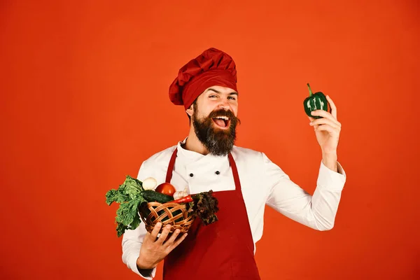 Mann mit Bart auf rotem Hintergrund. Chef hält Salat, Tomaten, — Stockfoto