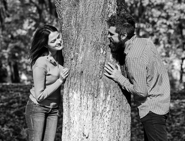Par i kärlek spelar bakom träd i höst park. — Stockfoto