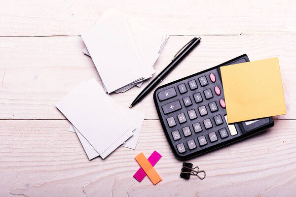 Канцелярские принадлежности и калькулятор. Наклейки желтого цвета рядом с ручкой