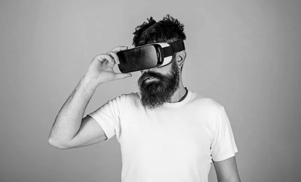 Homem com barba em óculos VR, fundo azul claro. Conceito de dispositivo VR. Cara com cabeça montada exibir interagir em realidade virtual. Hipster em face séria usar gadget moderno para explorar a realidade virtual — Fotografia de Stock