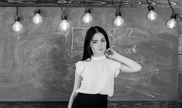 La profesora en la cara tranquila se para frente a la pizarra. Mujer con el pelo largo en blusa blanca se para en el aula. Concepto de escuela de élite. Profesor listo para comenzar la lección, copiar espacio — Foto de Stock