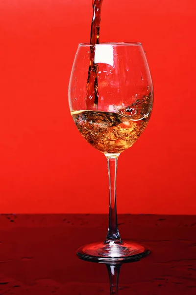 Splash of drink in wine glass on red background, side vie — Stock Photo, Image