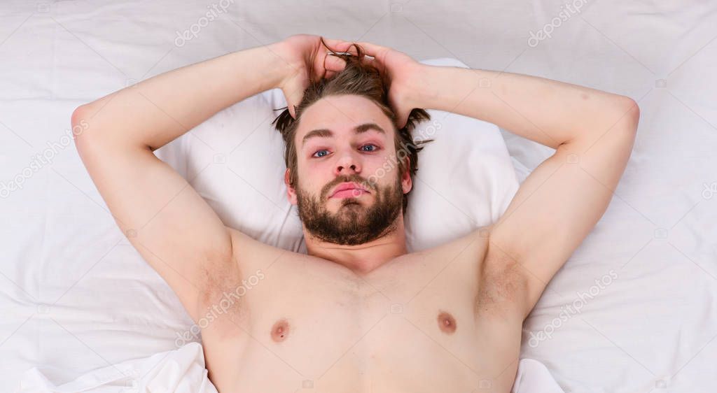Man stretching in bed. Picture showing young man stretching in bed. Man relaxing in bed.