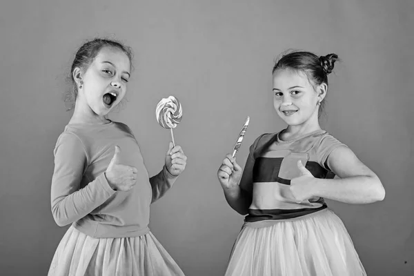 Meisjes eten grote kleurrijke zoete karamels. Kinderen met een blij gezicht — Stockfoto