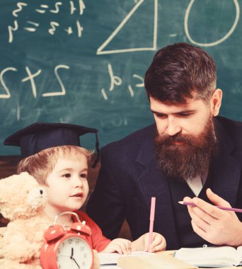 Çocuk çalışmaları dikkatle dinlerken öğretmen ile. İlköğretim kavramı. Öğretmen ve öğrenci kolej, kara tahta arka plan içinde. Baba oğul öğretir temel bilgi, tartışmak, açıklamak