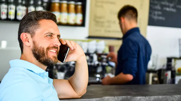 Man smartphone order coffee in cafe. Coffee break concept. Glad to hear you. Coffee take away option for busy people. Man mobile conversation cafe barista background. Drink coffee while waiting