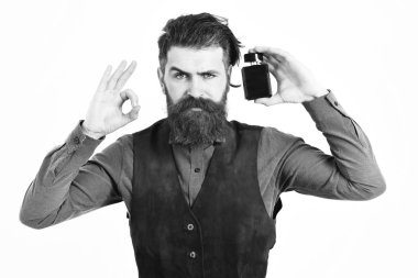 Sakallı adam ciddi bir parfüm tutuyor.