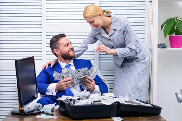 Homem feliz e animado sentado à mesa coberto de dinheiro e se alegra com secretária menina. Empresário com dinheiro no escritório. Conceito de corrupção. Moedas de dólar caindo . — Fotografia de Stock