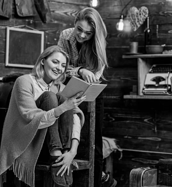 Chicas con caras alegres riendo de momento divertido en el libro. Mamá y su hija leyendo juntas en la fría noche de invierno. Vacaciones en familia en el campo casa de madera, concepto de actividad de ocio —  Fotos de Stock