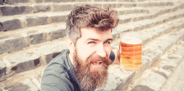 Le type se repose avec de la bière fraîche. Hipster sur le visage heureux à boire de la bière en plein air. Vendredi calme concept. Homme à la barbe et à la moustache tient le verre avec de la bière tout en étant assis sur des escaliers en pierre — Photo