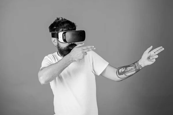 Shooting VR game. Man hand gesture as gun play shooter game in VR glasses. First person shooter shows how addictive VR could be. Man bearded hipster with virtual reality headset on red background