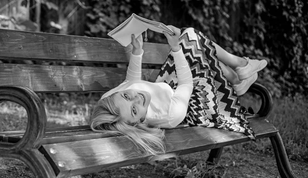 Interesting book. Smart and pretty. Smart lady relaxing. Girl lay bench park relaxing with book, green nature background. Woman spend leisure with book. Girl reading outdoors while relaxing on bench