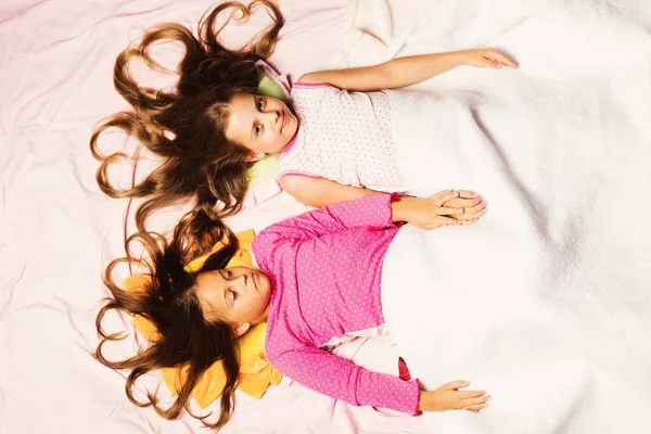 Дети с распущенными волосами лежат на розовом фоне — стоковое фото