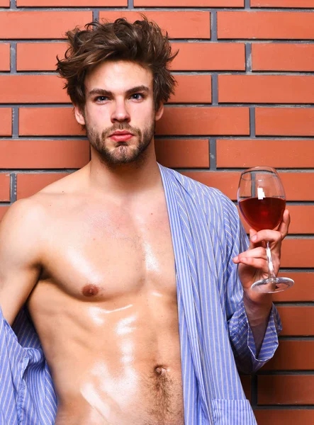 Concepto erótico y de deseo. Chico atractivo relajándose con bebida alcohólica. Hombre sexy pecho piel sudorosa celebrar wineglass. El soltero disfruta del vino. Macho tousled cabello degustar vino de lujo. Beber vino y relajarse — Foto de Stock