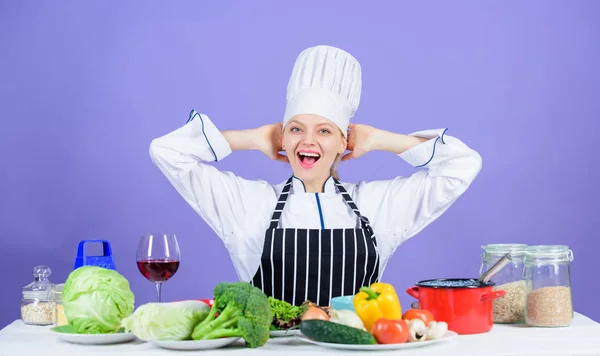 Lets start cooking. Woman chef cooking healthy food. Gourmet main dish recipes. Girl in hat and apron. Delicious recipe concept. Cooking healthy food. Fresh vegetables ingredients for cooking meal