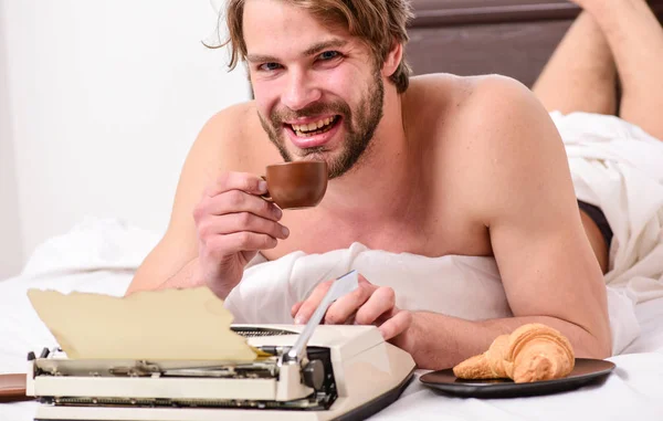 Daily routine of writer. Writer handsome author used old fashioned manual typewriter. Man writer lay bed with breakfast working. Morning bring fresh idea. Morning inspiration. Erotic literature
