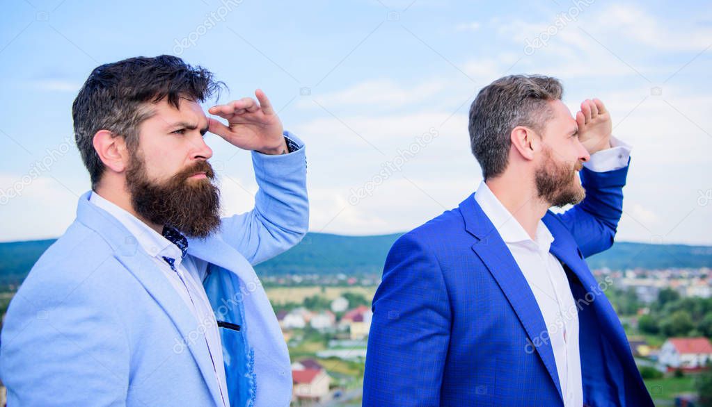 Developing business direction. Men formal suit managers looking at opposite directions. Changing course. New business directions. Businessmen bearded faces stand back to back sky background