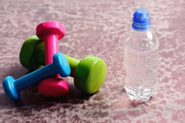 Plastik su şişesi Bordo arka plan üzerinde yakınındaki halter