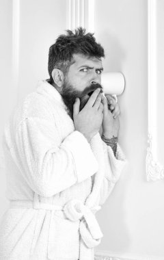 Bornoz şüpheli yüzündeki hipster gizlice konuşma dinle. Gizli ve casus kavramı. Casusluk, gizli dinleme beyaz iç adam. Adam sakal ve bıyık kupa duvarının yakınında kullanarak fıttırmış