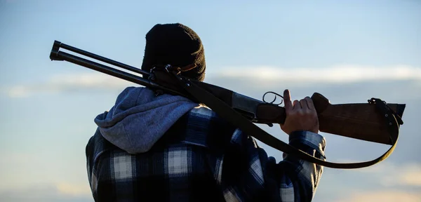 Brutalidad y masculinidad. Hunter lleva rifle en la mira trasera del hombro. Guy Hunter pasa tiempo libre cazando. Hombre tipo brutal guardabosques en el fondo de la naturaleza sombrero. Caza masculina hobby ocio concepto — Foto de Stock