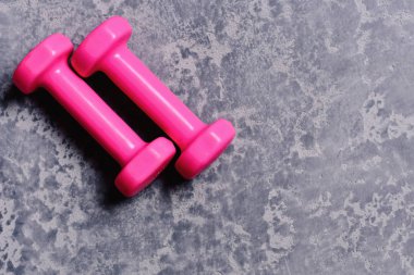 Gri doku arka plan üzerinde parlak pembe plastik dambıl