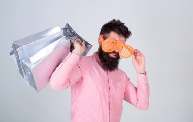 Alışverişe bağımlı tüketici. Bir sonraki tatiline nasıl hazırlanacağını. Sakallı hippi adam güneş gözlüğü takıyor, alışveriş torbası tutuyor. Kara Cuma 'da alışveriş. Kese kağıdıyla iyi alışverişler