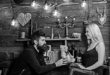 Gülümseyen yüzler üzerinde aşık çift tatilin keyfini çıkarın. Çift gamekeepers evde, ahşap iç arka plan romantik akşamın. Adam Bayan oyuncak ayı için yıldönümü hediye olarak vermek. Yıldönümü kavramı